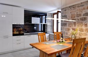 a kitchen with a wooden table and white cabinets at Lana & Ena Apartments in Kotor