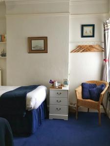 1 dormitorio con 1 cama y 1 silla en The Moorings B&B en Southend-on-Sea