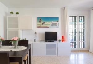 a living room with a tv on a white cabinet at Sandy Playa Golf Málaga con Parking in Málaga