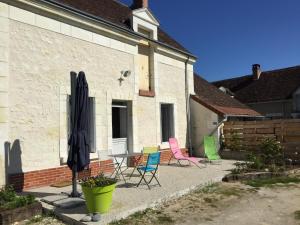 a group of chairs and an umbrella next to a building at Gîte de la Huppe in Noyers-sur-Cher