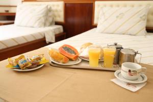 een dienblad met ontbijtproducten en drankjes op een bed bij Maison Florense Hotel in Sao Paulo