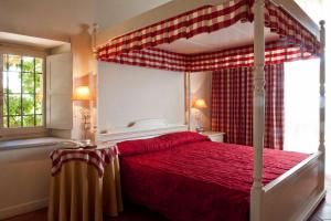 a bedroom with a canopy bed with red sheets at Tenuta La Cascinetta in Buriasco