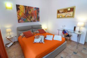 una camera da letto con letto con lenzuola arancioni e scrivania di B&B Neptunia fronte mare a Torre Specchia Ruggeri