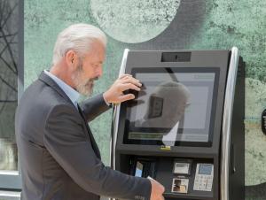 Un homme en costume utilisant une machine à atm dans l'établissement TT Aparthotel Neuhofen, à Neuhofen an der Krems