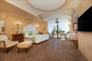 a bedroom with a bed and a chair and a tv at Palazzo Marziale in Sorrento