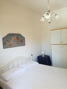 una camera da letto con un letto bianco e un dipinto sul muro di La casa del sole a Torre dell'Orso
