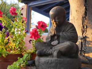 eine Statue eines Mönchs neben Blumen in der Unterkunft Ocea Retreat in Karlovasi