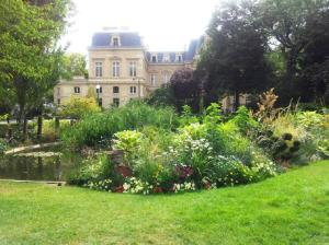 a garden in front of a large building at Le Marais Calme et lumineux in Paris