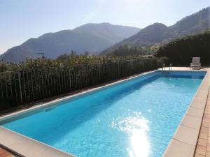 una grande piscina blu con montagne sullo sfondo di Appartamento Cristina - Rebomaholidays a Tignale