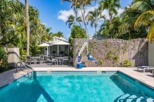 a swimming pool in a yard with palm trees at Southernmost Inn Adult Exclusive in Key West