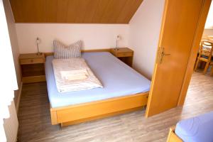 - un petit lit dans une petite chambre avec 2 tables dans l'établissement BORKUMUNTERKUNFT - WOH6 - IM HERZEN DER INSEL, à Borkum