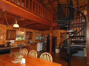 a kitchen with a table and a spiral staircase at Cedarwood Lodge in Penfield