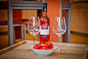 zwei Weingläser, eine Flasche und eine Schale Erdbeeren in der Unterkunft Haus Weinbergblick in Haigerloch