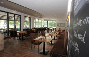 um restaurante com mesas e cadeiras de madeira e janelas em ACQUA Strande Yachthotel & Restaurant em Strande