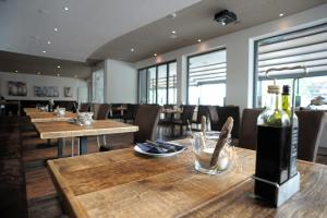 uma sala de jantar com mesas de madeira e garrafas de vinho em ACQUA Strande Yachthotel & Restaurant em Strande
