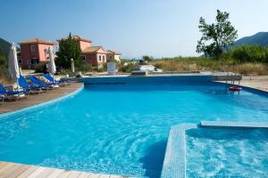 una gran piscina azul con sillas azules y montañas en Calypso Luxury Studios, en Vasiliki