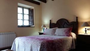 1 dormitorio con 1 cama con manta rosa y ventana en Casa Belarmina, en Cangas de Onís