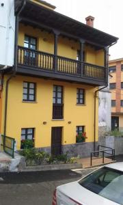 Una casa amarilla con balcón en la parte superior. en Casa Belarmina, en Cangas de Onís