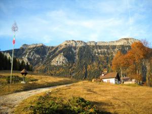 a field with a house and mountains in the background at Locanda Ponte Serra in Lamon