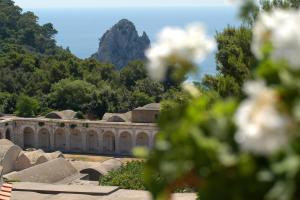 a stone building with a mountain in the background at Hotel La Tosca in Capri