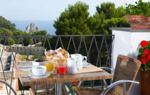 uma mesa de madeira com comida para o pequeno-almoço numa varanda em Hotel La Tosca em Capri