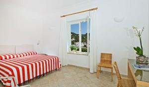 a white bedroom with a bed and a window at Hotel La Tosca in Capri