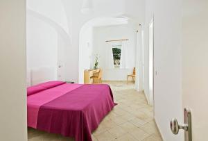 Camera bianca con letto e coperta viola di Hotel La Tosca a Capri