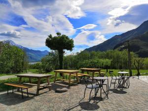 a group of picnic tables and chairs with mountains in the background at Agriturismo Val Codera in Verceia
