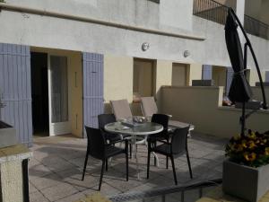 - une terrasse avec une table et des chaises dans un bâtiment dans l'établissement Résidence Les Écureuils, à Gréoux-les-Bains