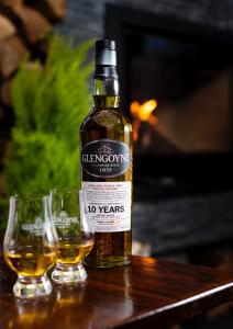 a bottle of whisky sitting on a table with two glasses at Ben Cruachan Inn - Restaurant, Pub with Rooms in Loch Awe