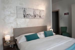 a bedroom with a white bed with two blue pillows at Le Suites - di fronte Ospedale Sacro Cuore in Negrar