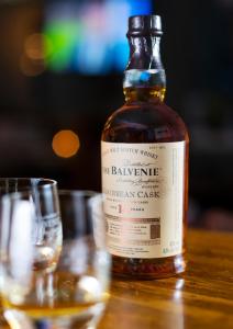 a bottle of whiskey sitting on a table next to a glass at Ben Cruachan Inn - Restaurant, Pub with Rooms in Loch Awe +5 photos
