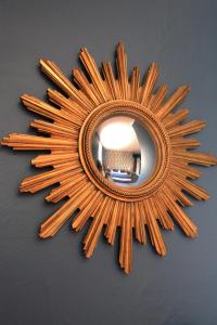 a mirror with a sunburst design on a wall at La bohème - Chambres d’hôtes in Senlis