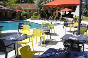 un restaurant avec des tables et des chaises jaunes à côté d'une piscine dans l'établissement Domaine de la Petite Isle - Luberon, à LʼIsle-sur-la-Sorgue