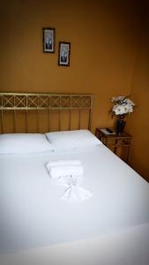 1 dormitorio con 1 cama blanca y un jarrón de flores en Pousada Praia da Costa en Vila Velha