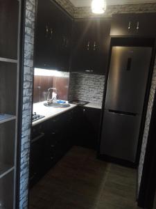 var-ketili في تبليسي: مطبخ مع دواليب سوداء وثلاجة حديد قابلة للصدأ