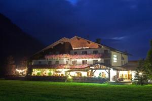 a building with flowers on the side of it at night at Gasthof Enzian in Tannheim