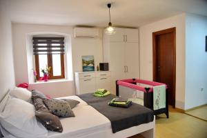 ein kleines Schlafzimmer mit einem Bett mit einer rosa und schwarzen Decke in der Unterkunft Lana & Ena Apartments in Kotor