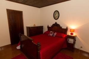 ein Schlafzimmer mit einem roten Bett und einer Uhr an der Wand in der Unterkunft Casa do Galante in Porto Judeu