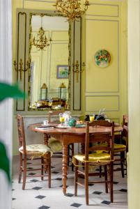 een eetkamer met een tafel en stoelen en een spiegel bij La Maison Charmante in Châtellerault