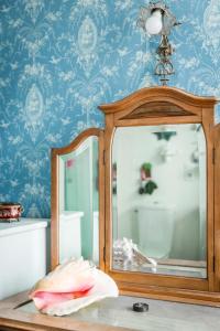 a mirror sitting on a table in a room with blue wallpaper at La Maison Charmante in Châtellerault +69 photos