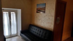 un sofá de cuero negro en una sala de estar con ventana en La casetta dei Desideri, en Poggio Bustone
