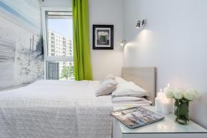 a bedroom with a bed and a table with a magazine at Elite Apartments Downtown Premium in Gdańsk