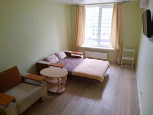 キーウにあるПосуточная аренда квартиры м. Левобережнаяのベッド1台、ソファ、窓が備わる小さな客室です。