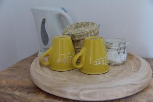 three yellow mugs sitting on a wooden cutting board at Bed & Breakfast IL PAJO in Padenghe sul Garda