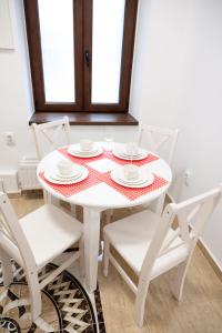 een witte tafel met witte stoelen en een rode en witte tafelkleed bij Samuel House in Sibiu