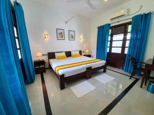 a bedroom with a bed and blue drapes at Coastal Villa Mirissa in Mirissa
