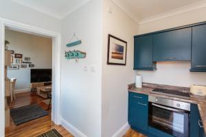 een keuken met blauwe kasten en een woonkamer bij Beach Hideaway in Lytham St Annes