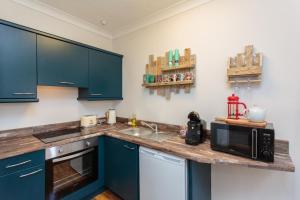 een keuken met blauwe kasten en een aanrecht met een magnetron bij Beach Hideaway in Lytham St Annes