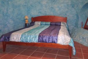ein Holzbett in einem Schlafzimmer mit blauer Wand in der Unterkunft Casa-Cueva Nijar in Níjar